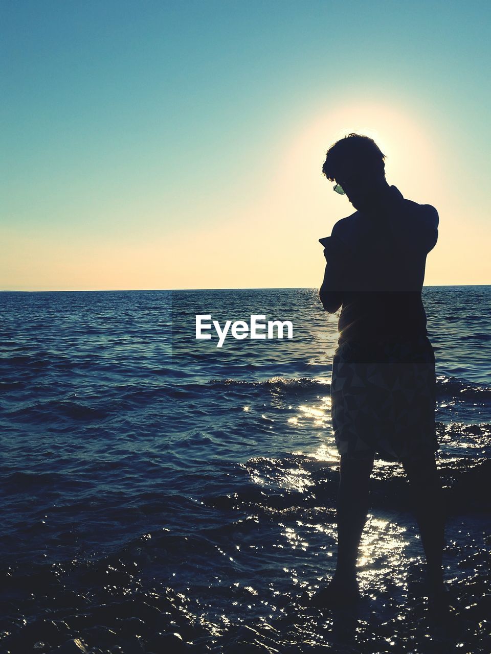 SILHOUETTE MAN STANDING AT BEACH AGAINST SKY DURING SUNSET