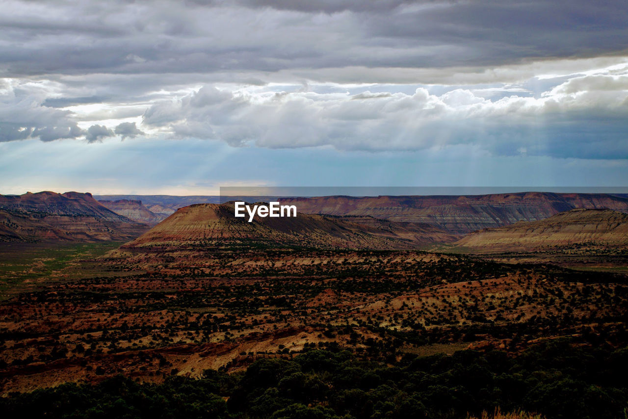 Scenic view of desert landscape against cloudy sky