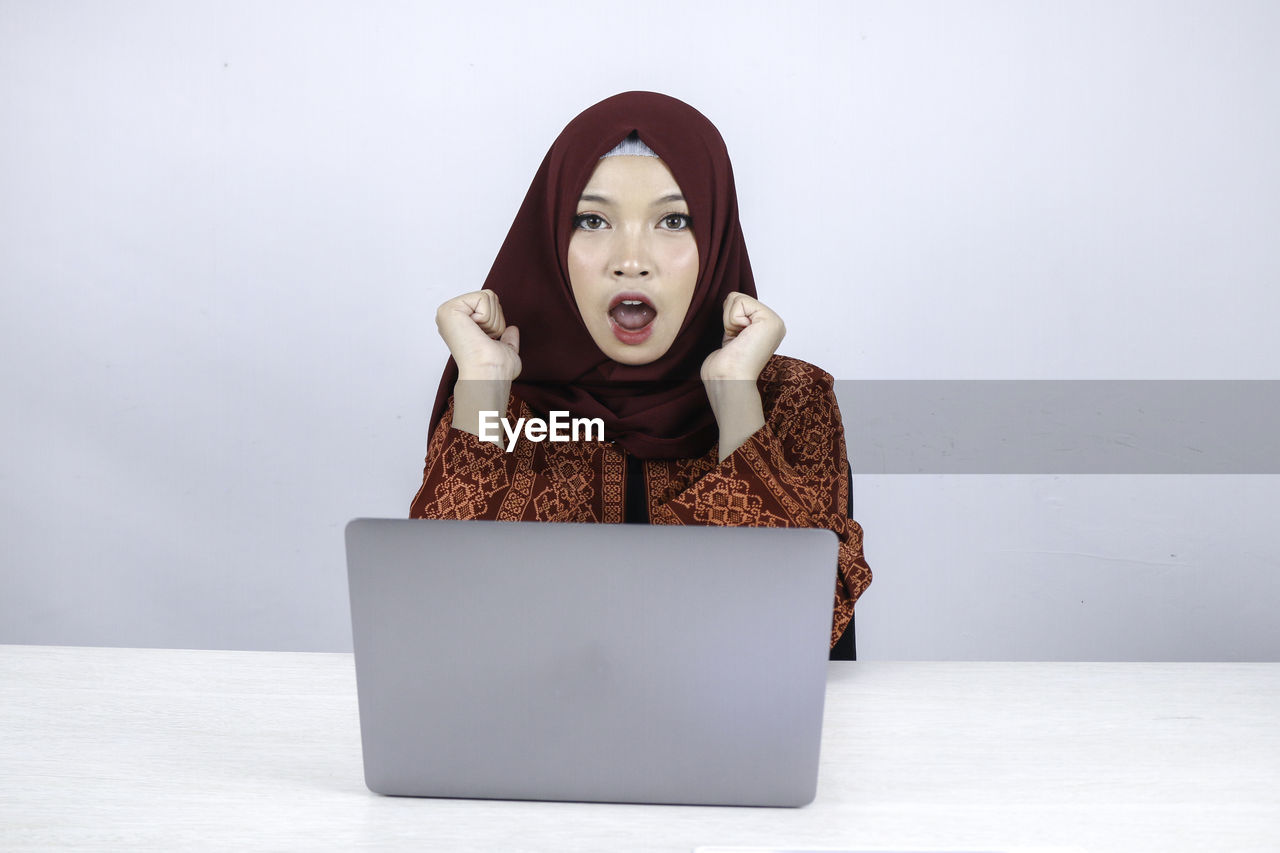 PORTRAIT OF YOUNG WOMAN USING LAPTOP