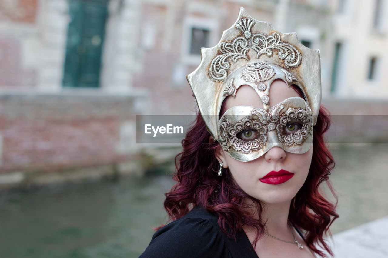 Portrait of woman wearing mask by canal during carnival