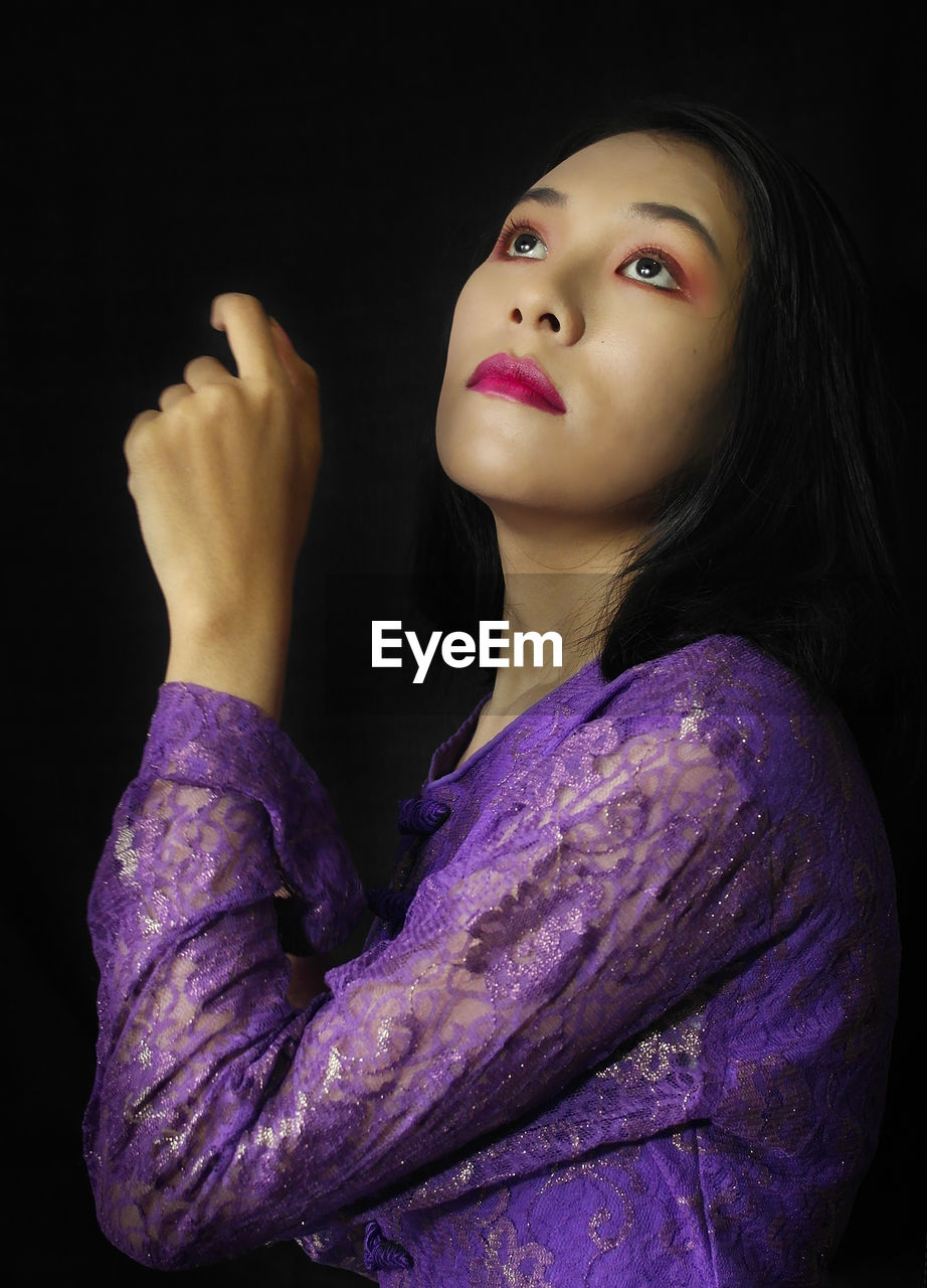 Portrait of a beautiful young woman over black background