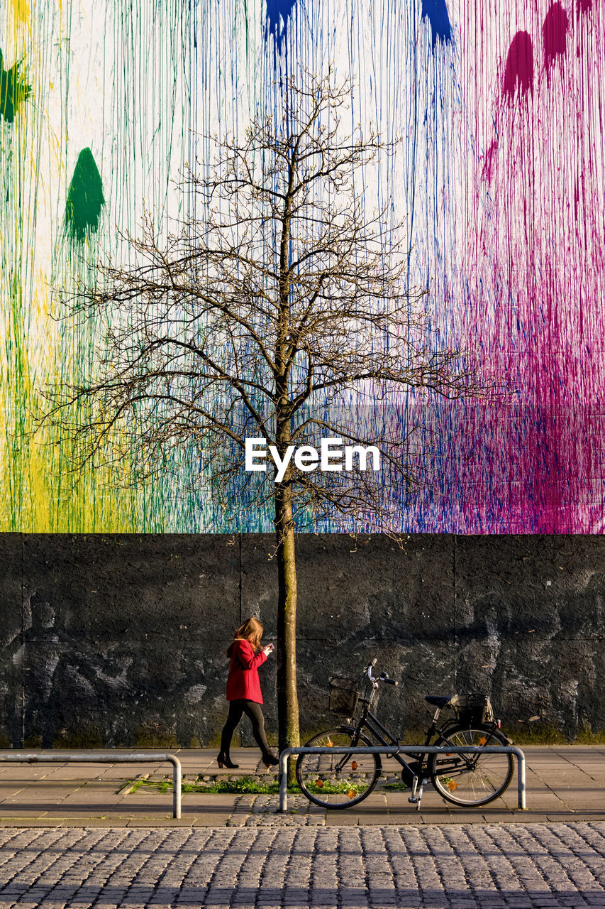 FULL LENGTH OF MAN WITH UMBRELLA ON TREE AGAINST SKY