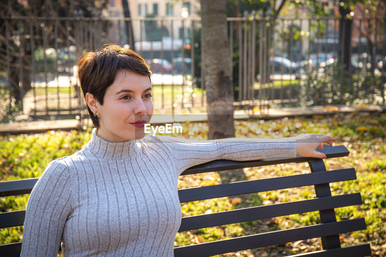 The young woman is sitting on a park bench in rome. 