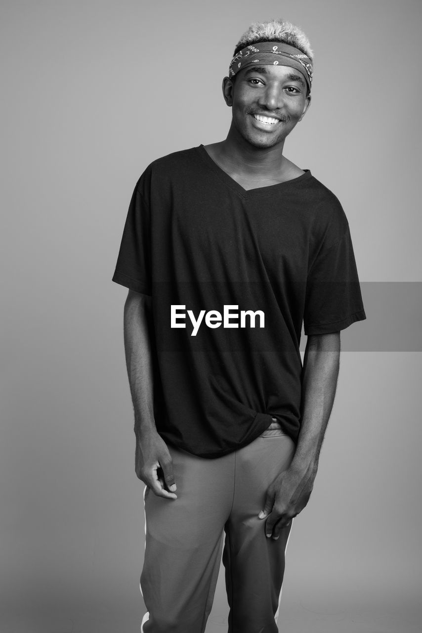 Young man standing against gray background