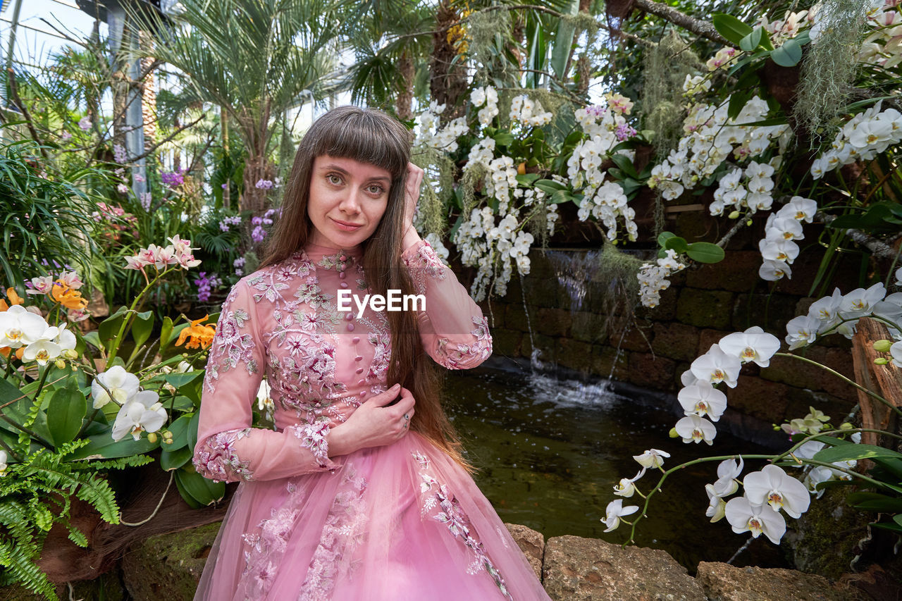 PORTRAIT OF BEAUTIFUL WOMAN STANDING BY PINK FLOWER