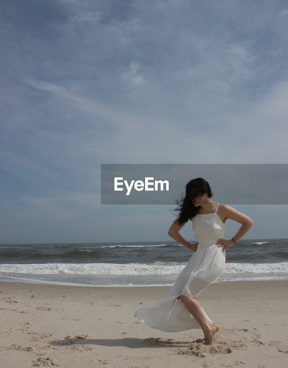 Woman posing at beach against sky