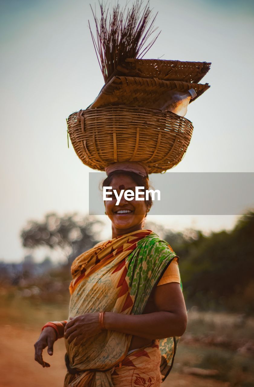 Portrait of smiling woman carrying wicker basket outdoors