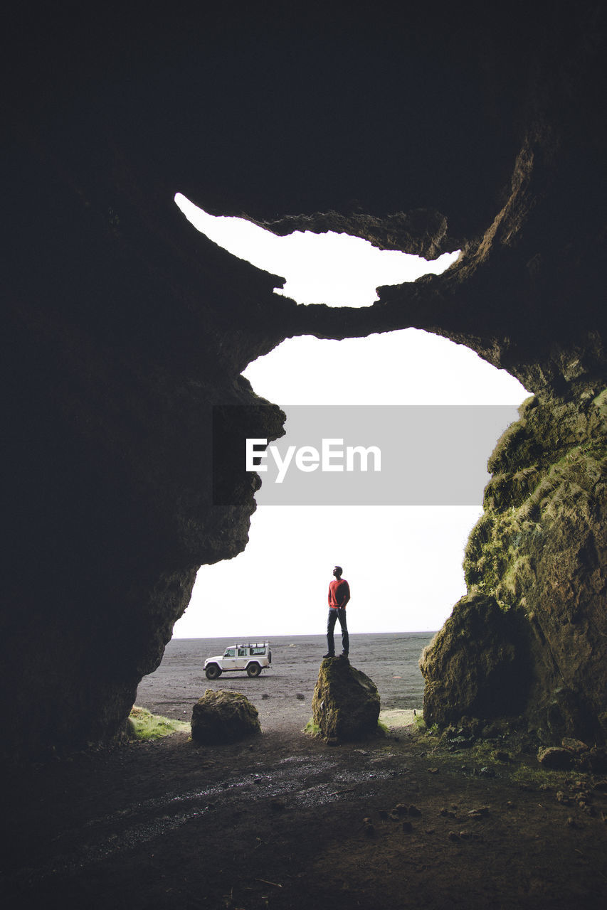 MAN STANDING ON CLIFF BY SEA