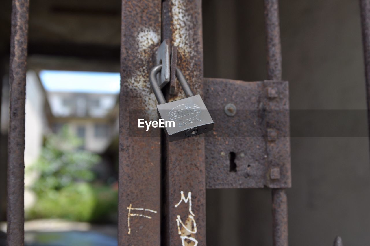 Low angle view of padlock on rusty metallic gate