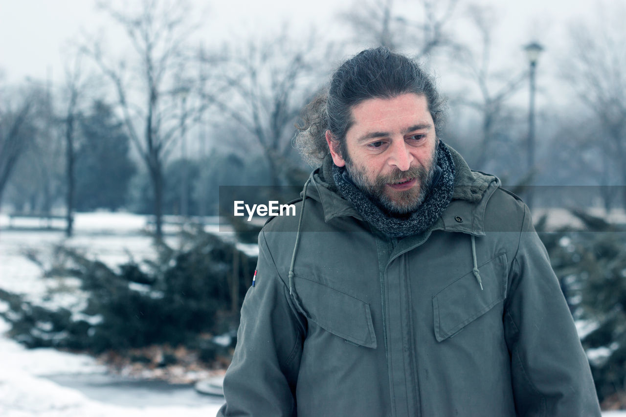 Close-up of man in warm clothing against bare trees during winter