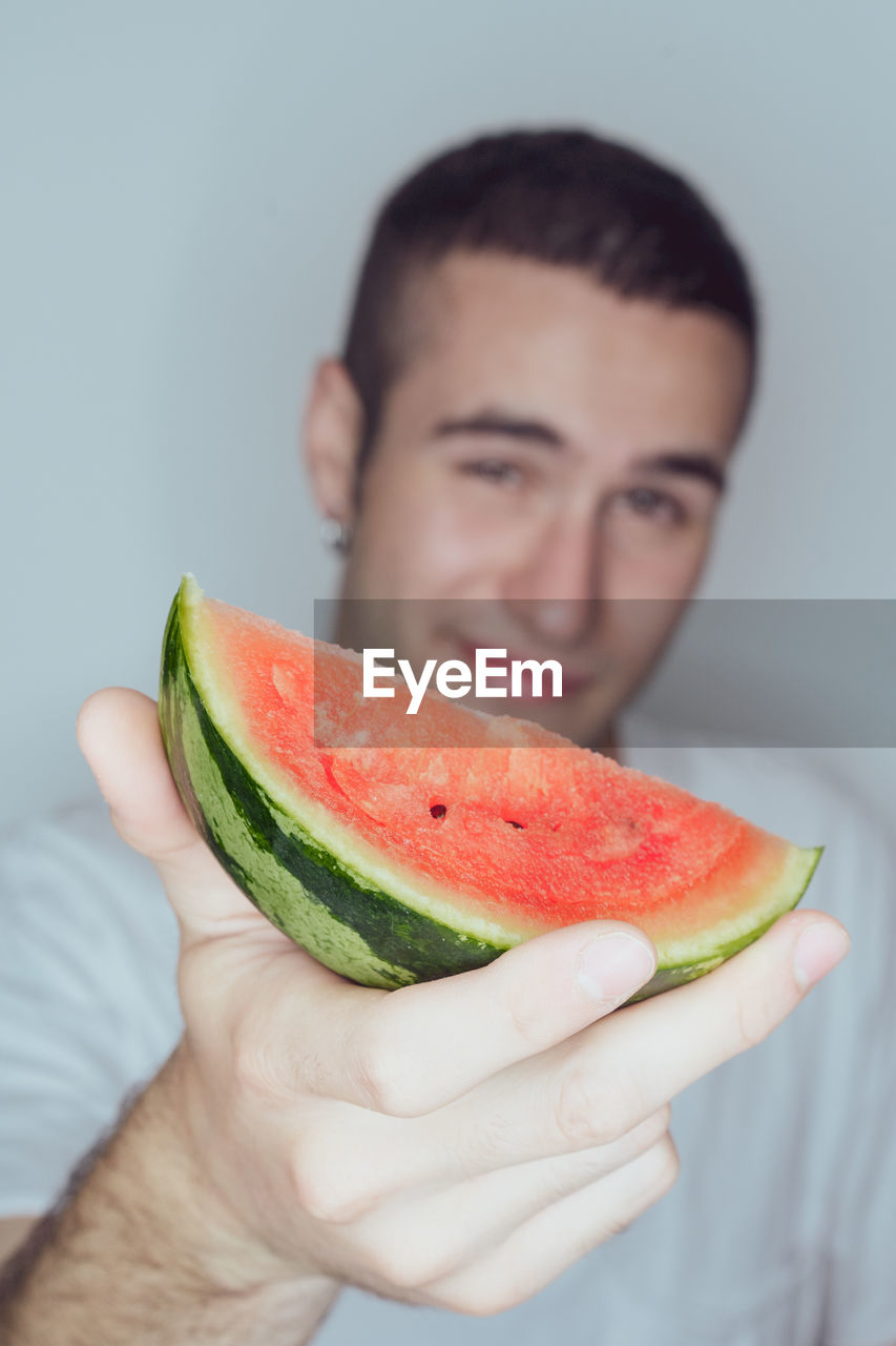 Portrait of smiling young man holding watermelon