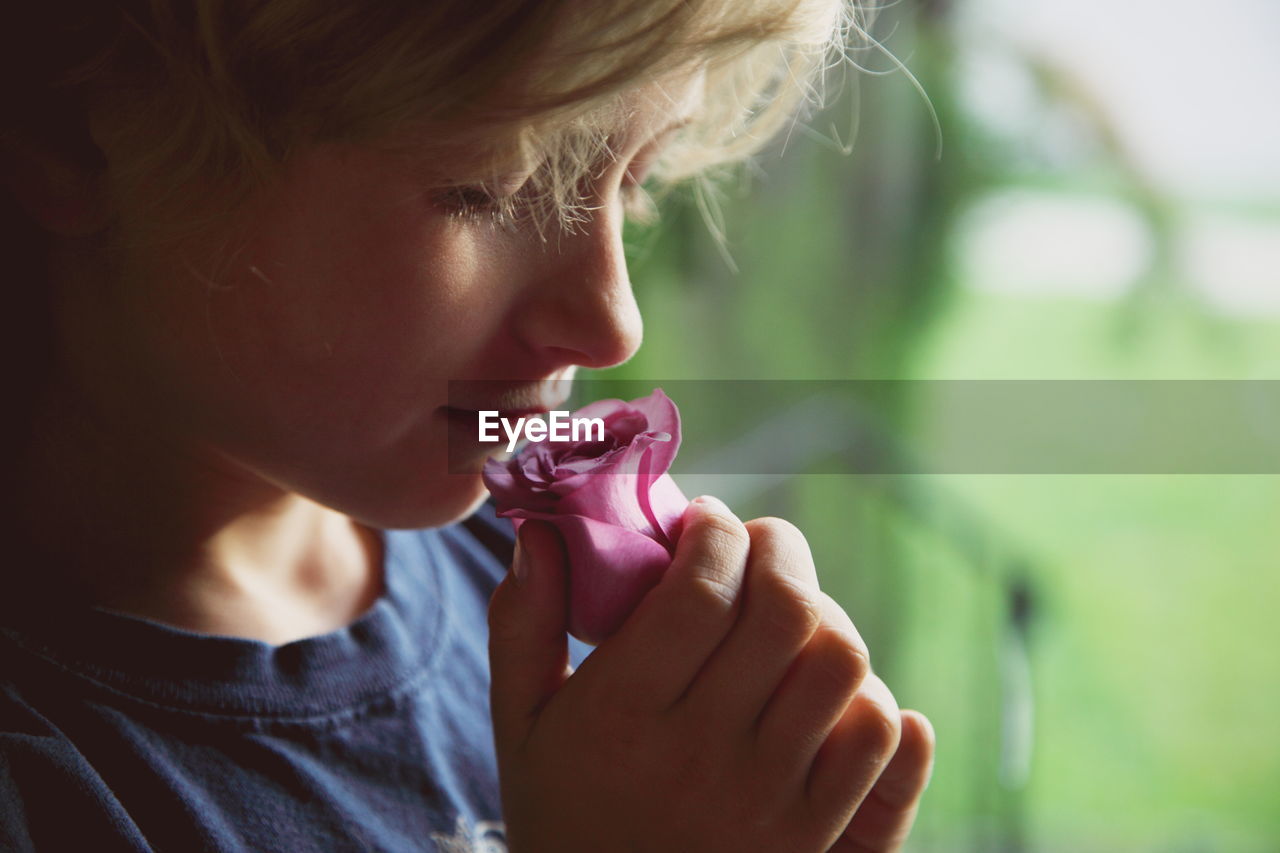 Close-up of boy smelling on rose