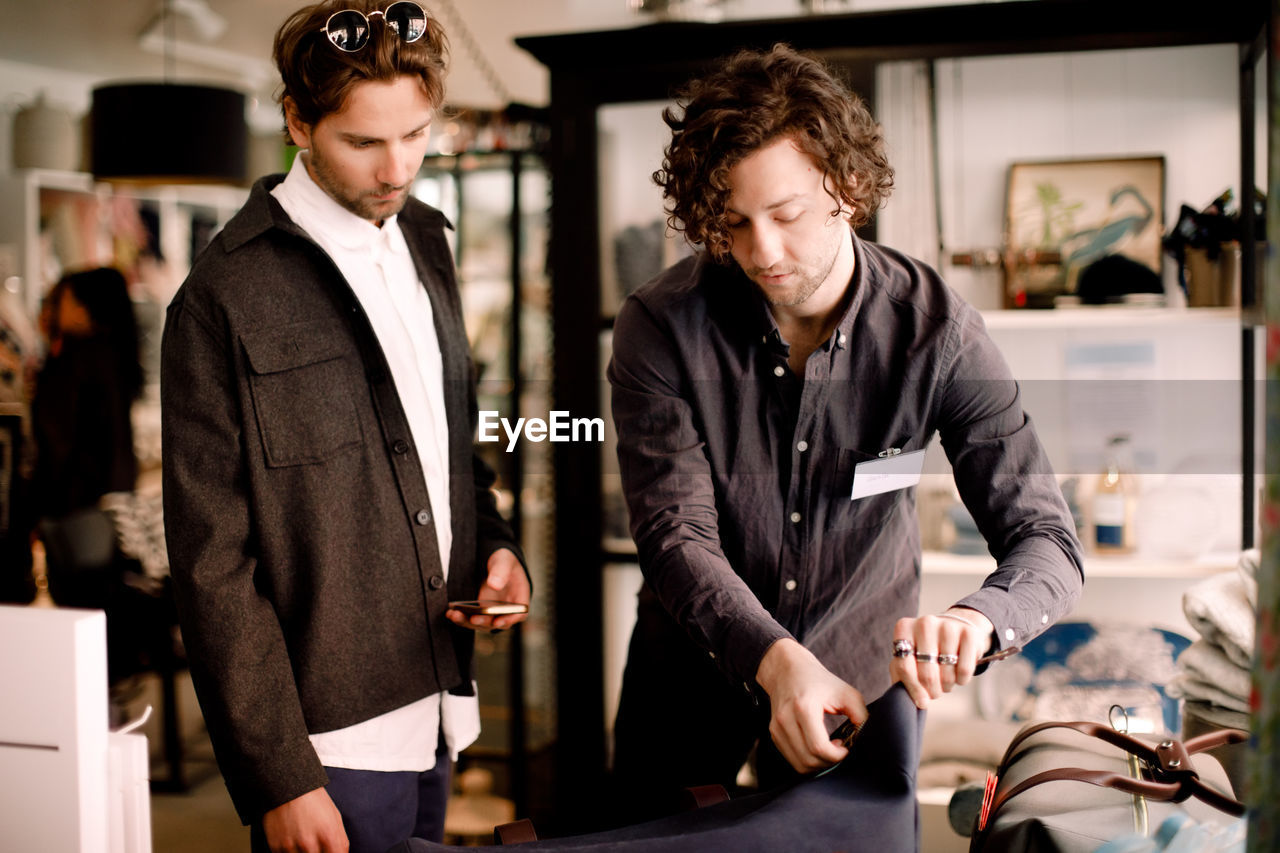 Salesman showing luggage bag to male customer at retail store