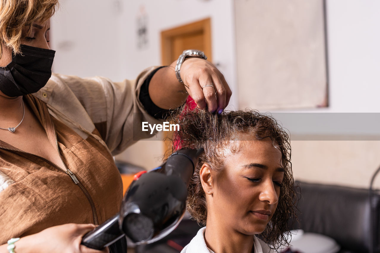 Hairdresser styling customer hair at salon