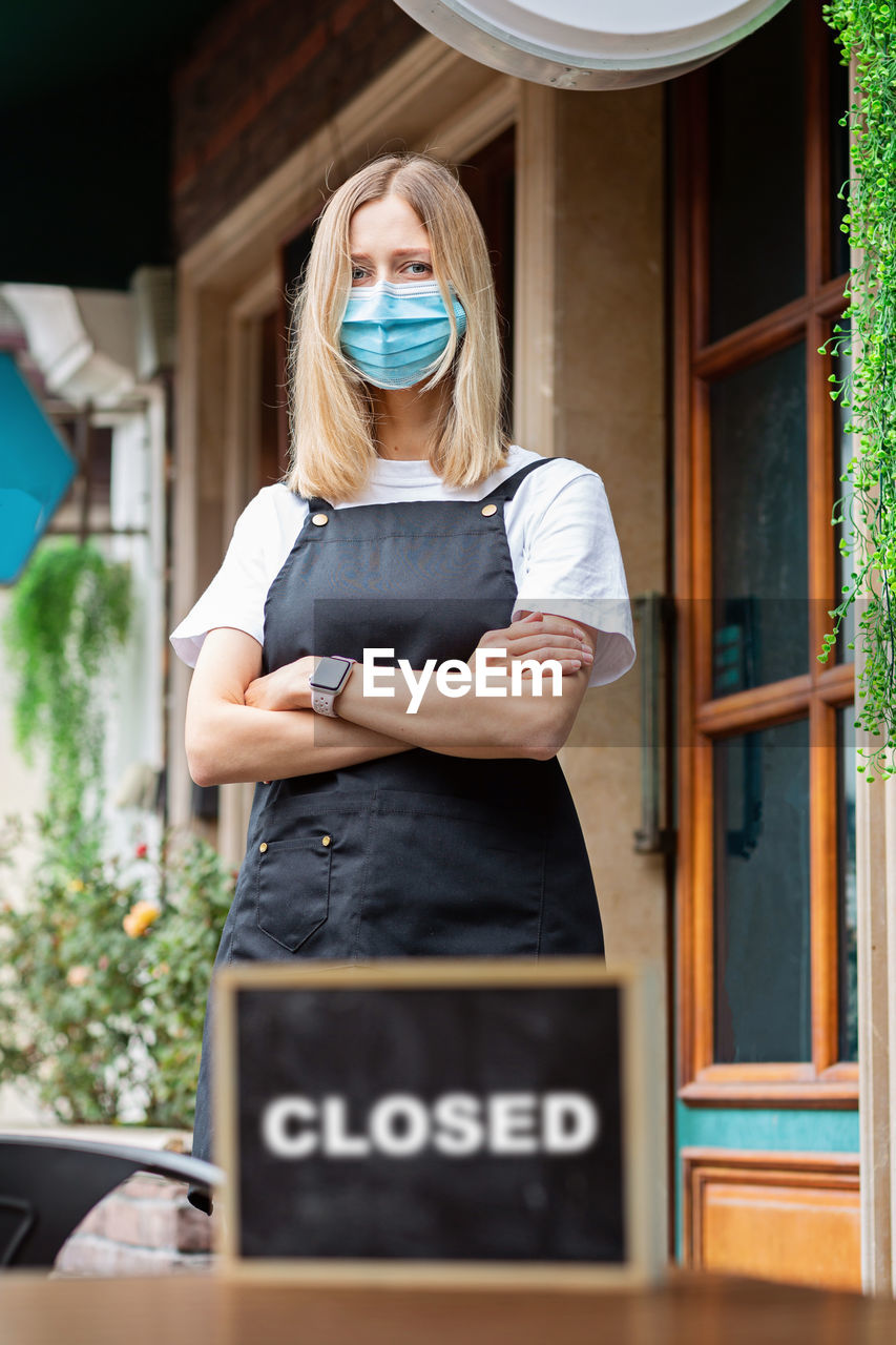 Caucasian waitress woman wearing medical mask, cafe closed. coronavirus covid-19 pandemic