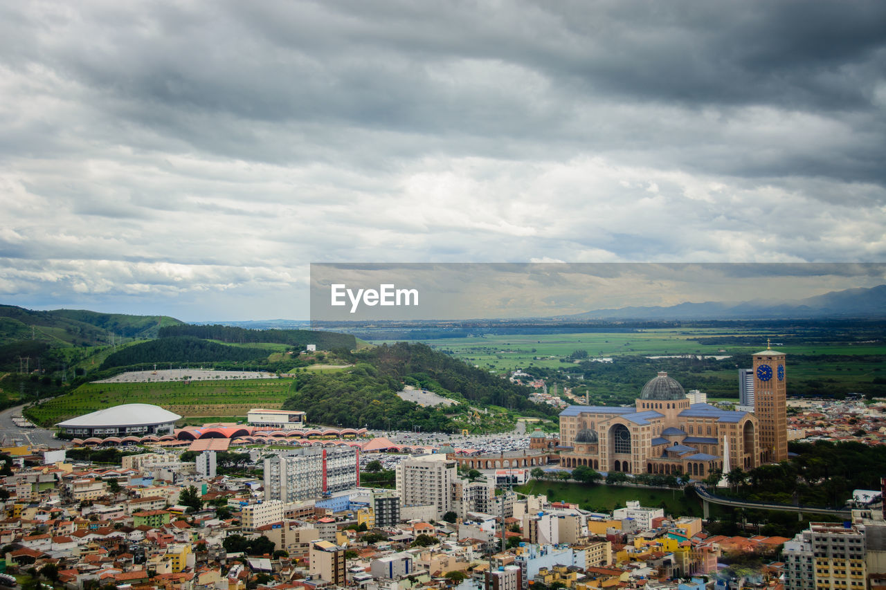 HIGH ANGLE VIEW OF TOWNSCAPE AGAINST CLOUDY SKY