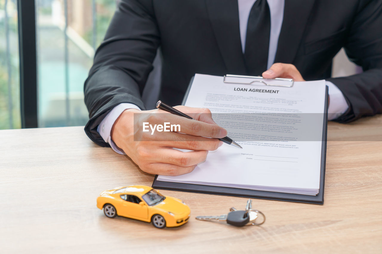 Midsection of businessman showing loan agreement at desk in office