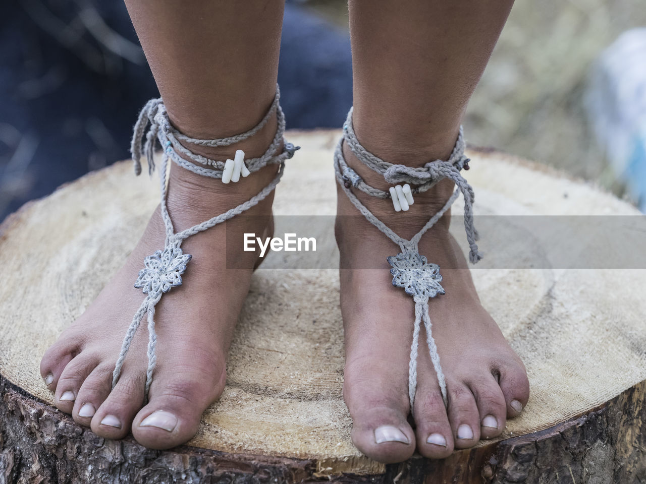 Low section of woman wearing anklet on tree stump