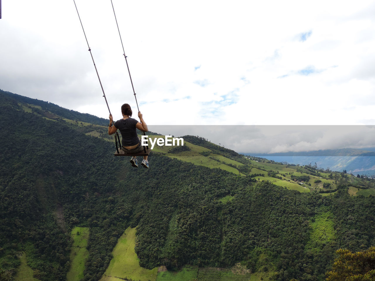 Woman swinging over mountains against sky