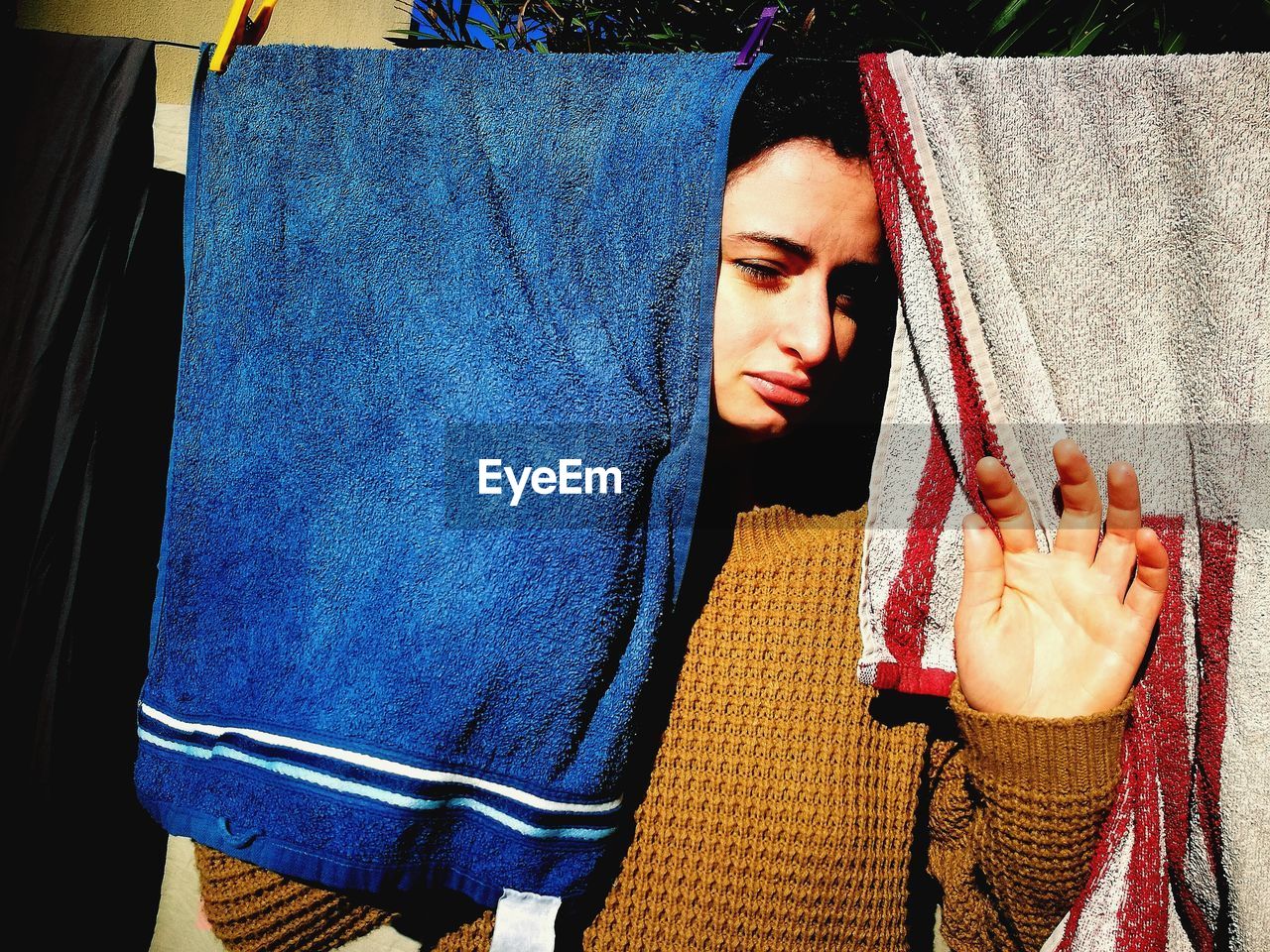 Young woman standing amidst towels drying