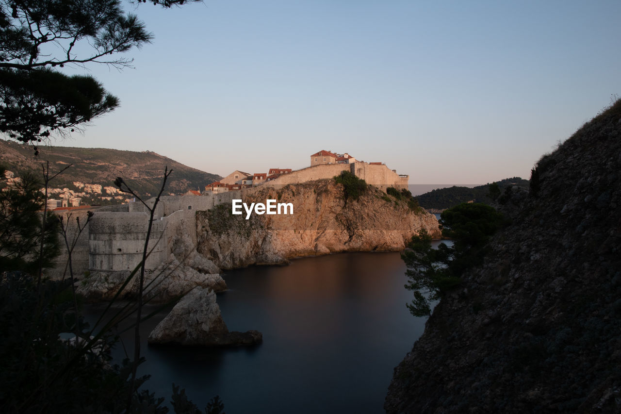 Scenic view of river by buildings against clear sky