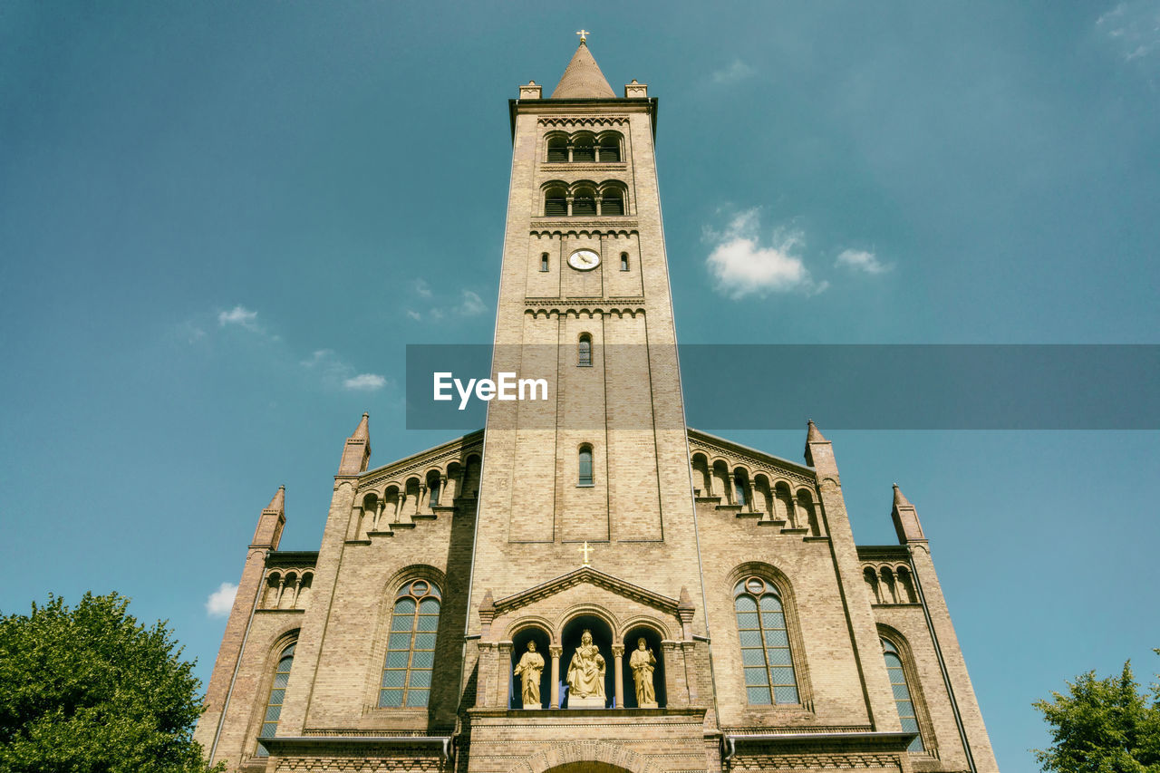 Low angle view of church against blue sky during sunny day