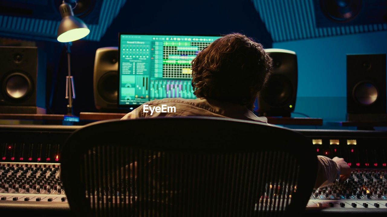 rear view of man sitting in train at night