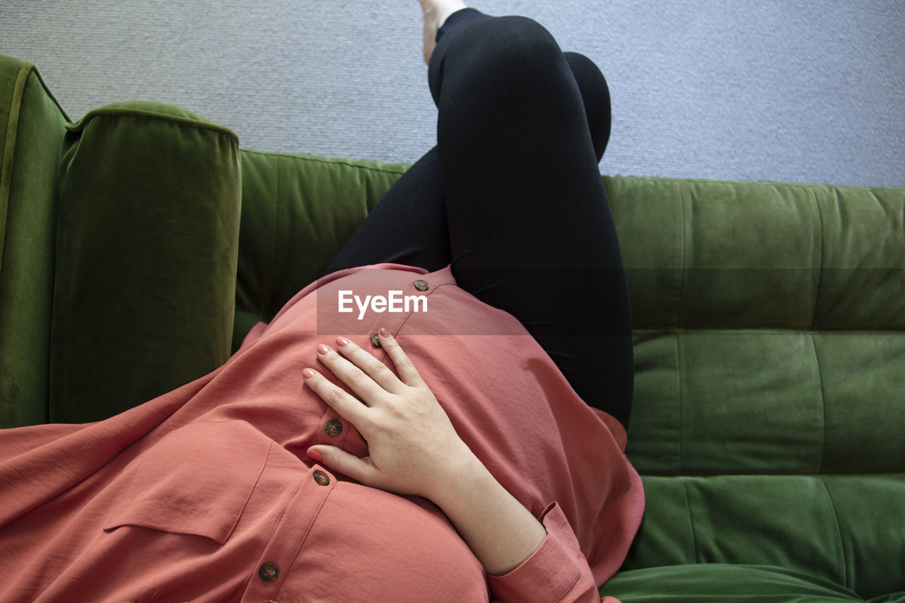 Midsection of woman sitting on sofa at home