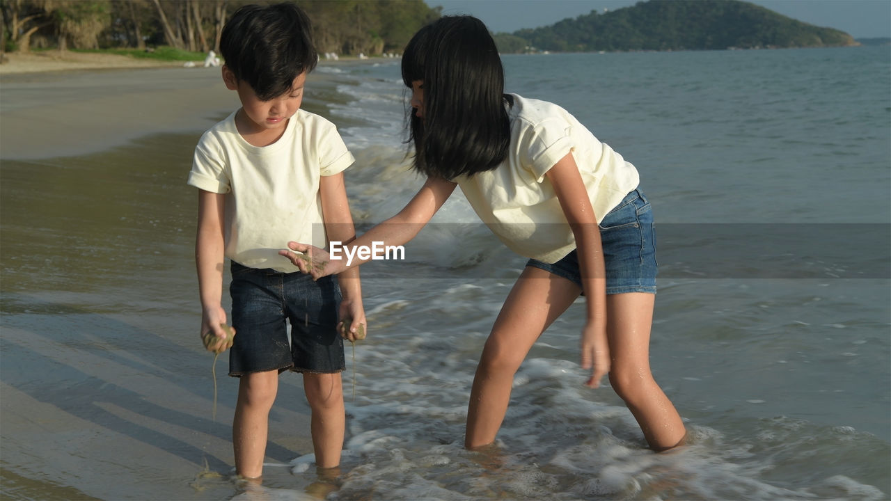 REAR VIEW OF FRIENDS ENJOYING IN WATER