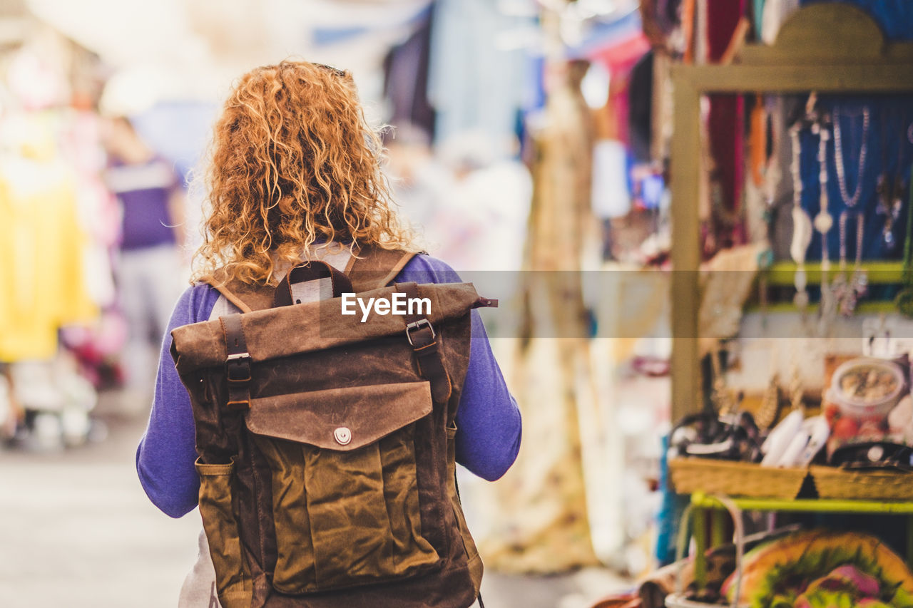 Rear view of woman with backpack standing at market