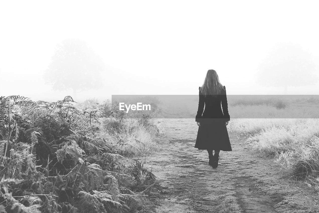 Rear view of woman walking on field during winter