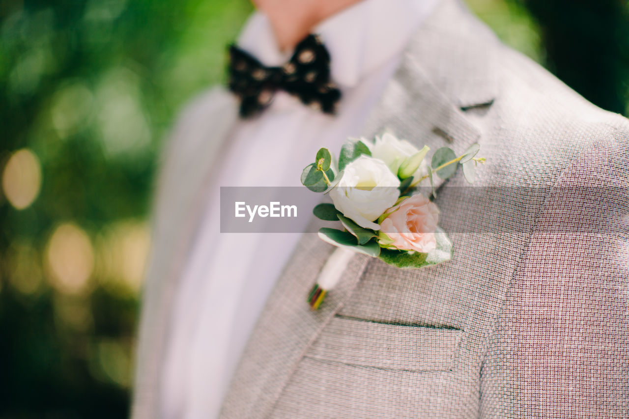 Midsection of bridegroom wearing boutonniere on suit