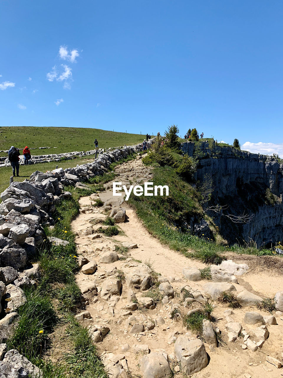 PEOPLE WALKING ON ROCKS AGAINST SKY