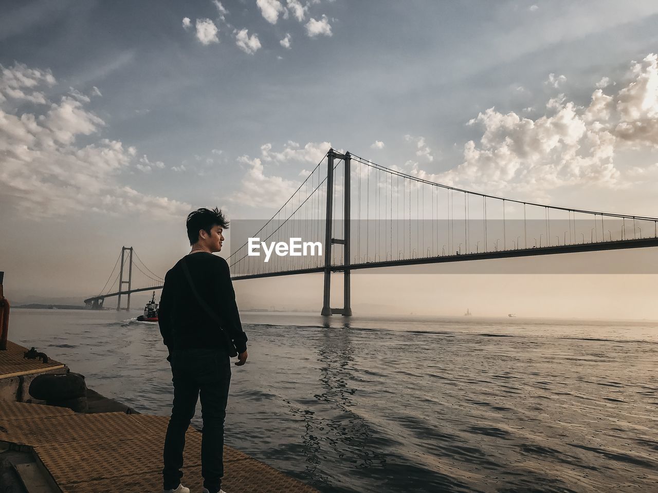 Man looking at bridge over sea