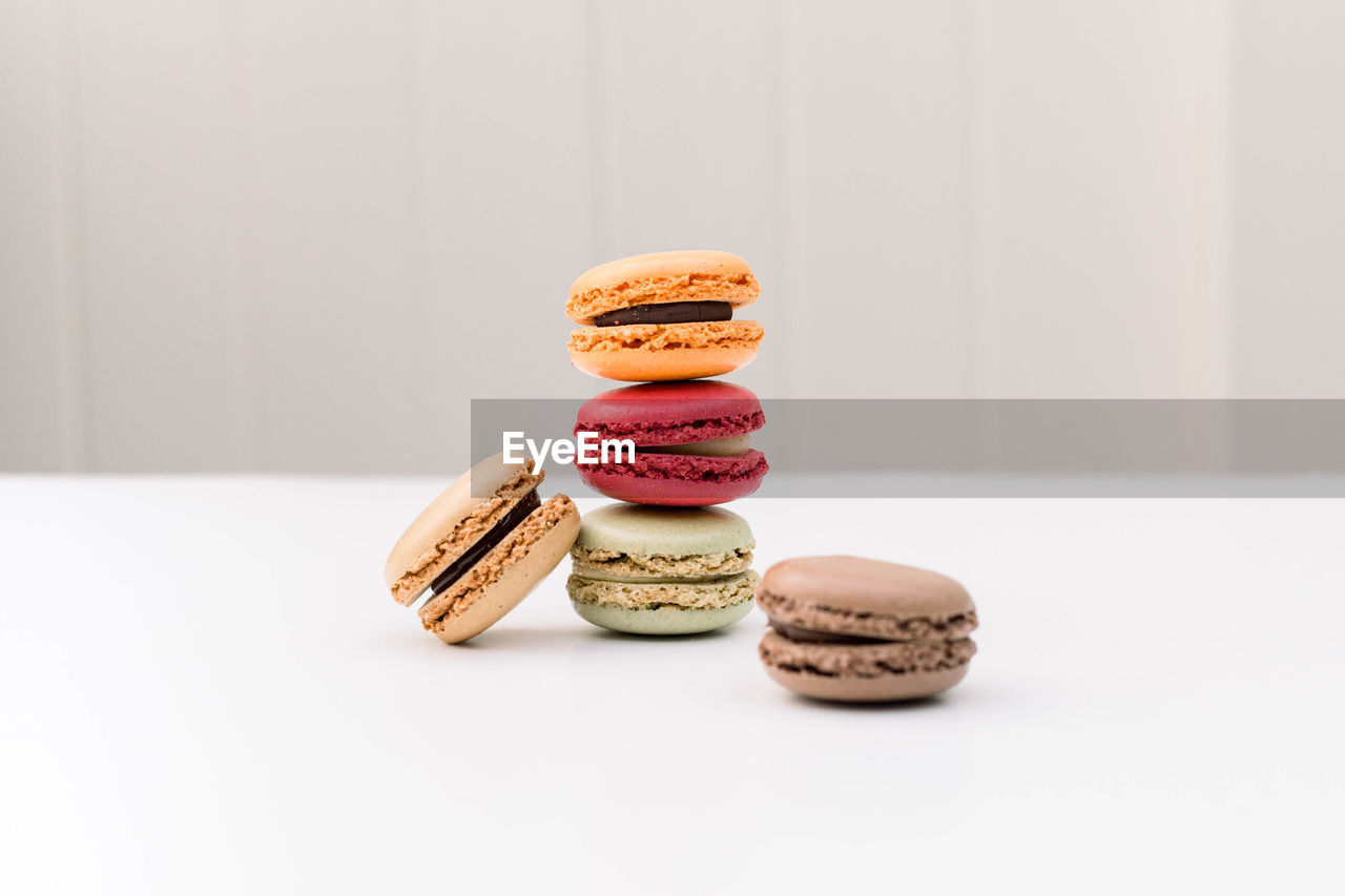Close-up of colorful macaroon cookies stalked up against white background
