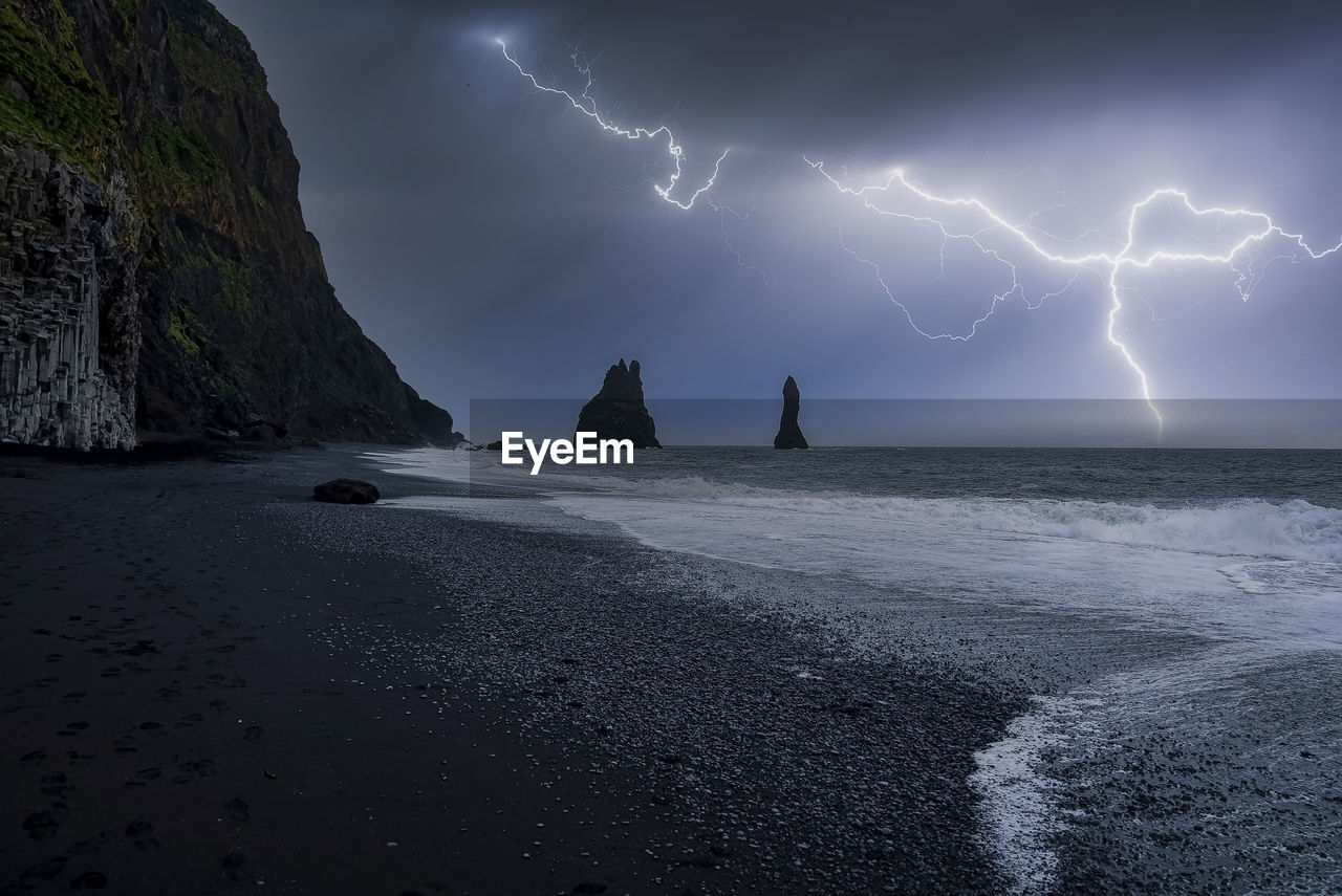 Idyllic view of lightning at black reynisfjara beach against stormy night