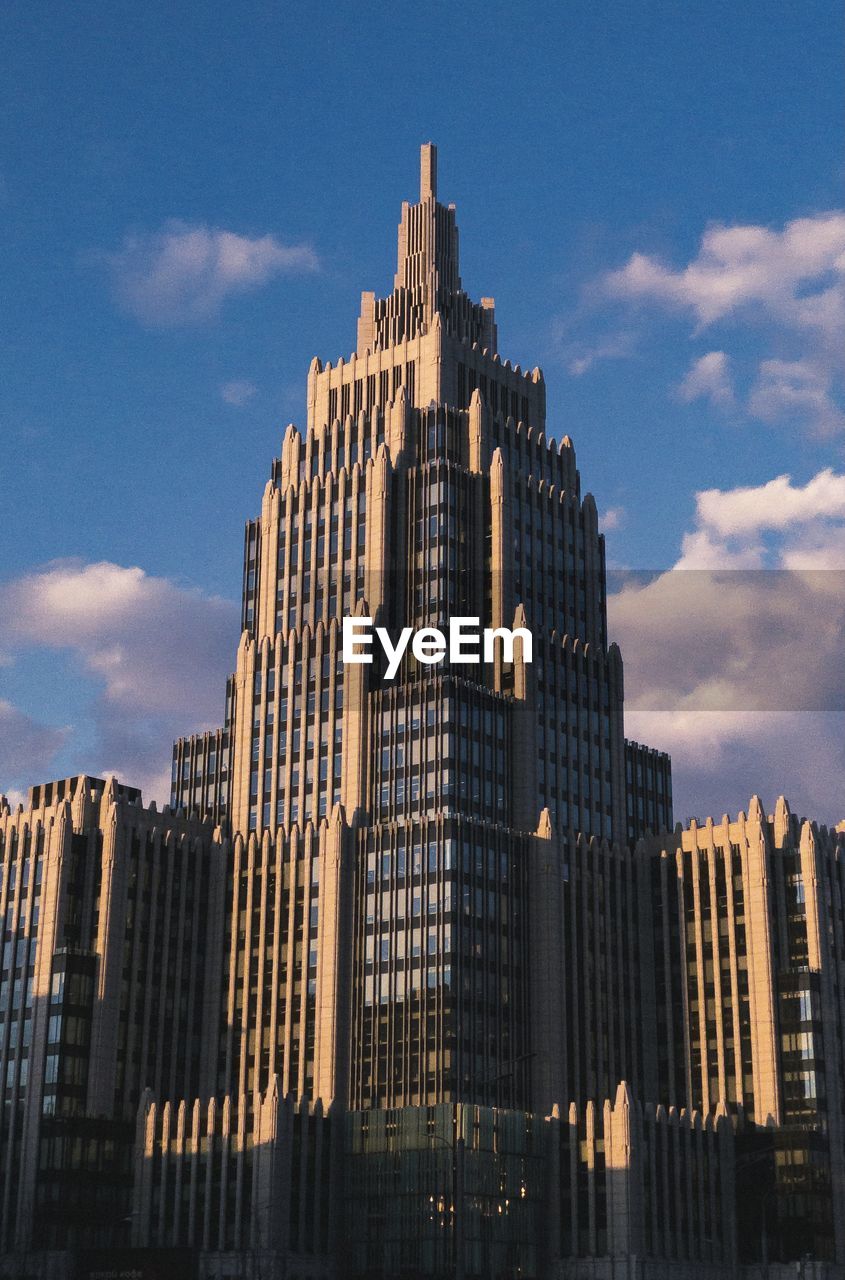 Low angle view of soviet buildings against cloudy sky