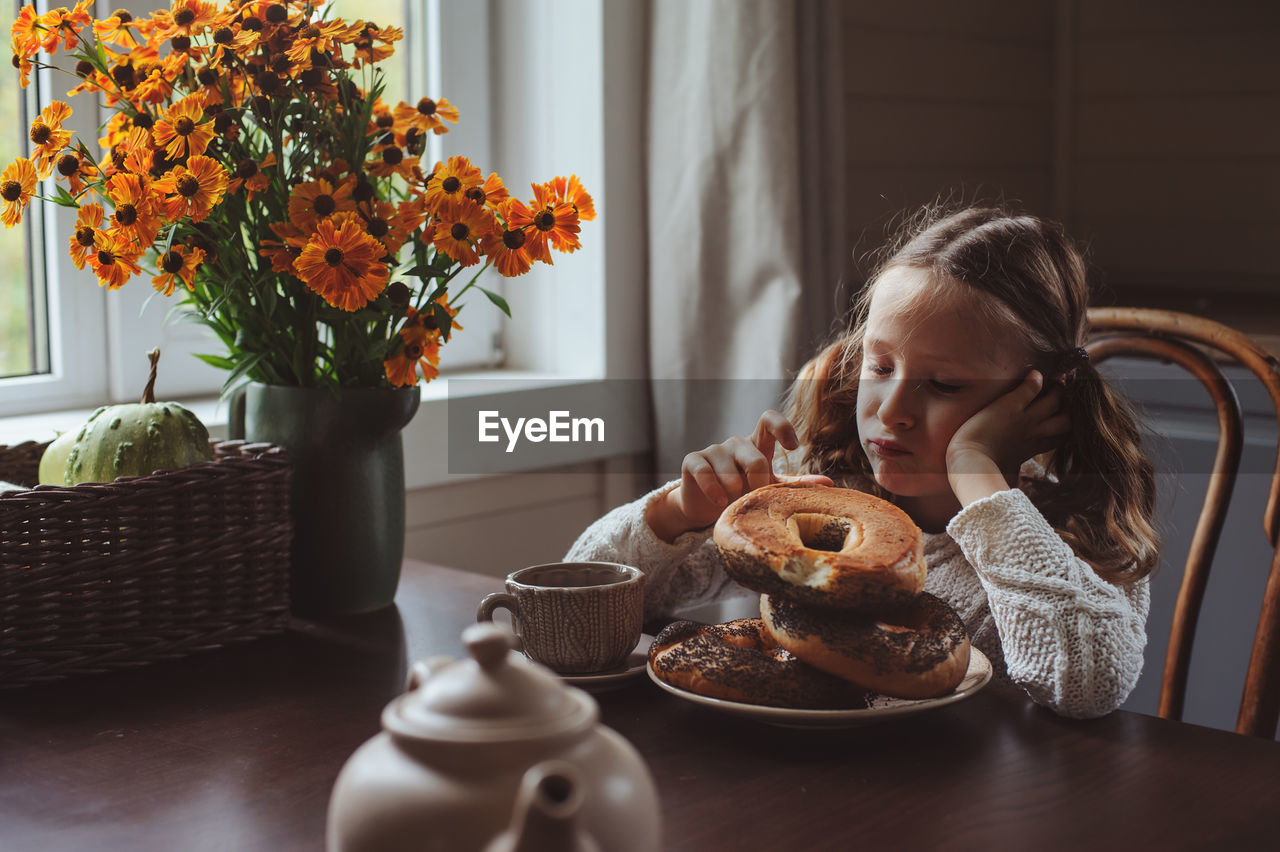 Cute girl having breakfast on table at home