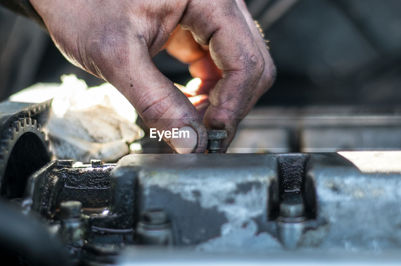 Cropped hand of mechanic working on engine of car