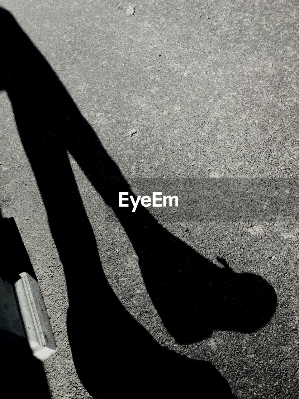 Silhouette of woman's legs on asphalt