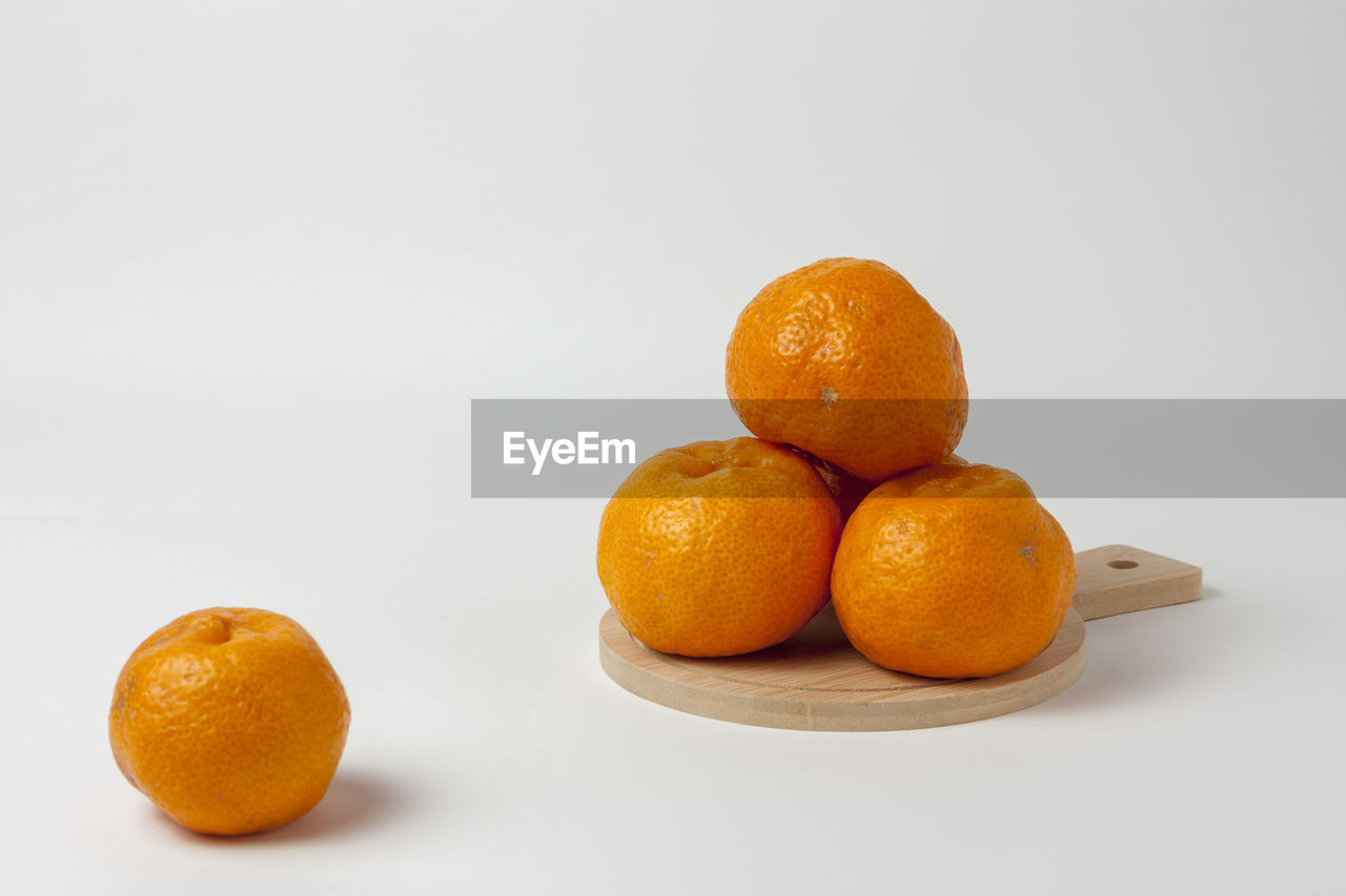 Orange fruits on cutting board over white background