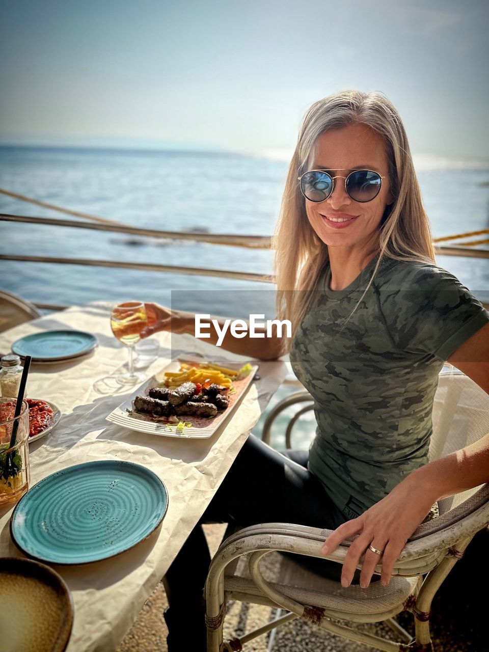 portrait of young woman wearing sunglasses while sitting on table
