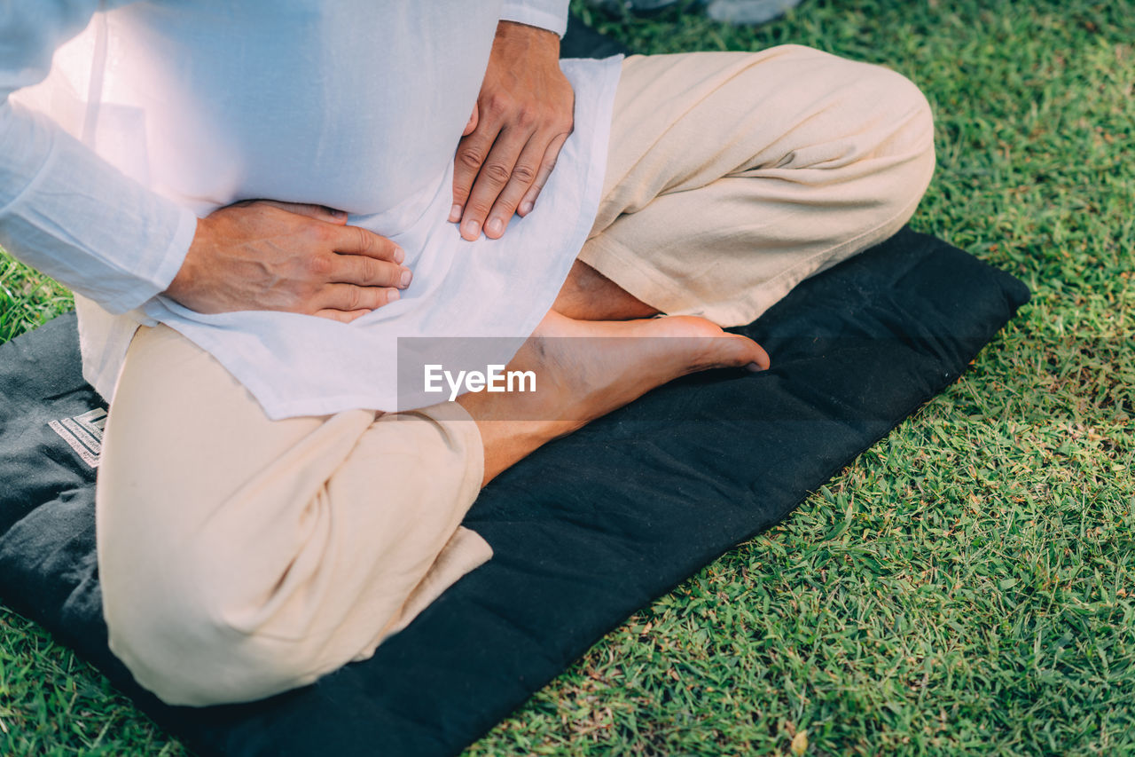 Male therapist performing reiki therapy self treatment holding hands over his stomach