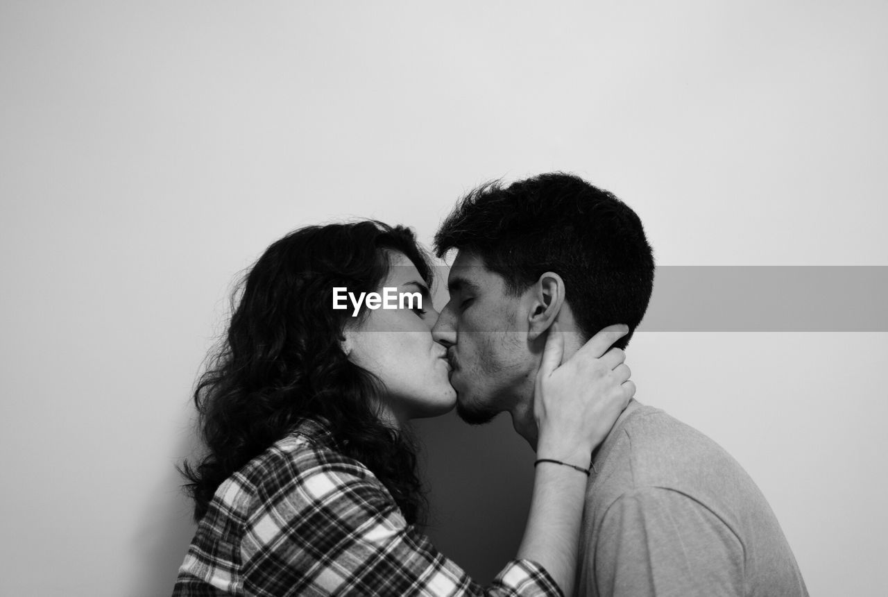 Side view of couple kissing against white background