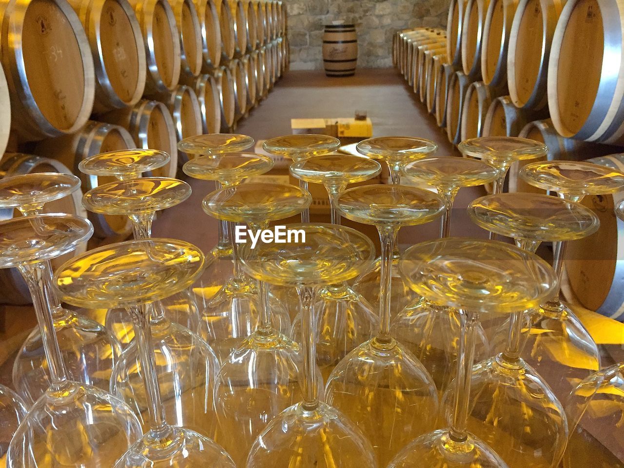Upside down wineglasses on table against barrels in cellar