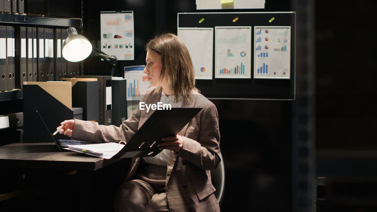 rear view of young woman using mobile phone while standing in office