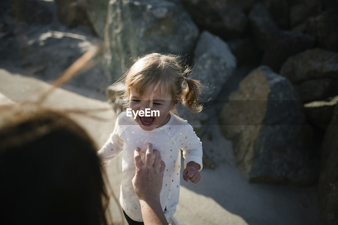 Cropped image of mother tickling cheerful daughter at beach