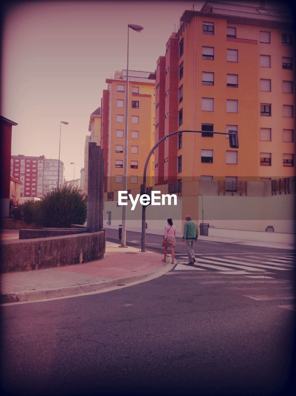 MAN CROSSING ROAD AGAINST BUILDINGS