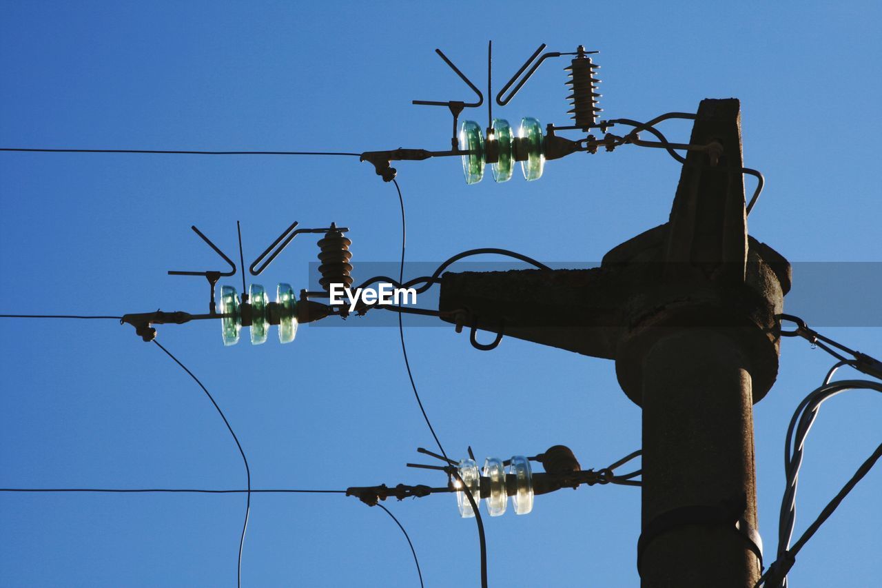 Low angle view of electricity pylon against blue sky