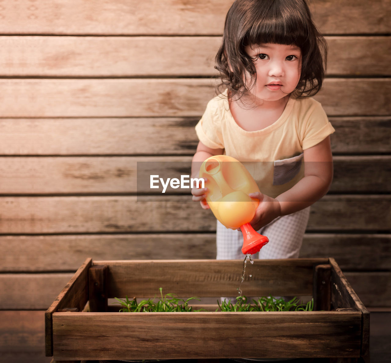 Close-up portrait of baby girls watering plants